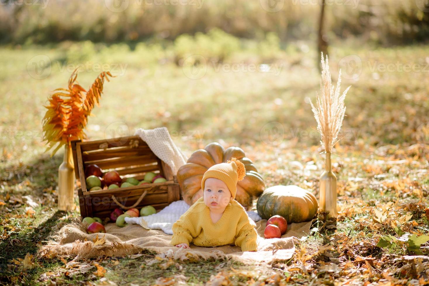 linda niña sentada en calabaza y jugando en el bosque de otoño foto