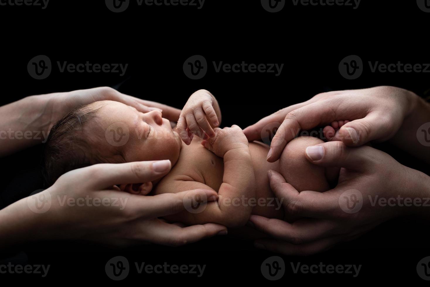 Parents hold their newborn son in their arms. Picture taken on a dark background. photo