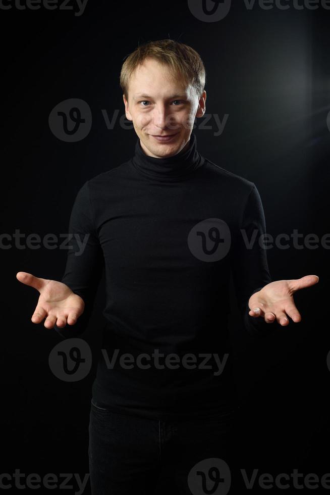 Portrait of determined goodlooking man wearing black shirt, black background. photo