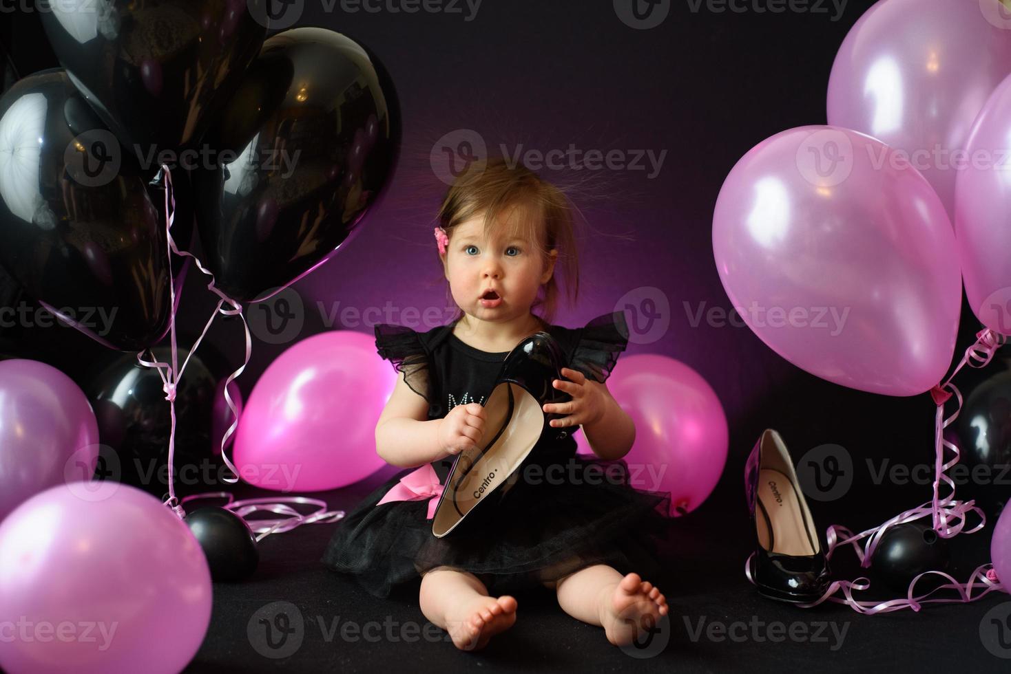 día de la fiesta de cumpleaños de la niña del primer año. globos y vacaciones en interiores. cumpleaños del niño niña bonita en su primer vestido negro foto