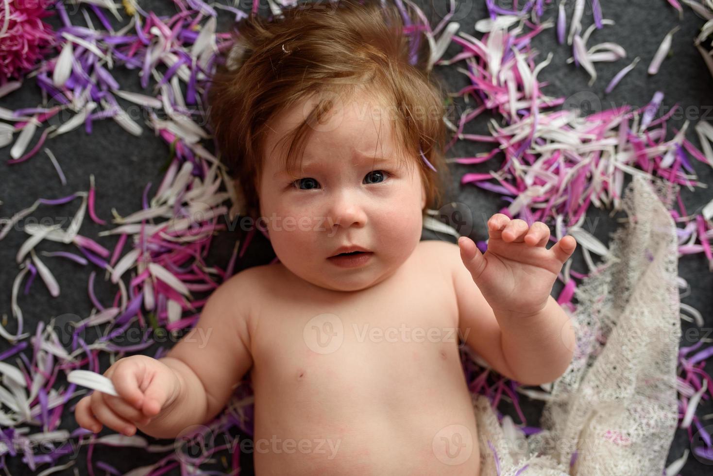 Portrait of a sweet little baby girl with a wreath of flowers on her head indoors photo