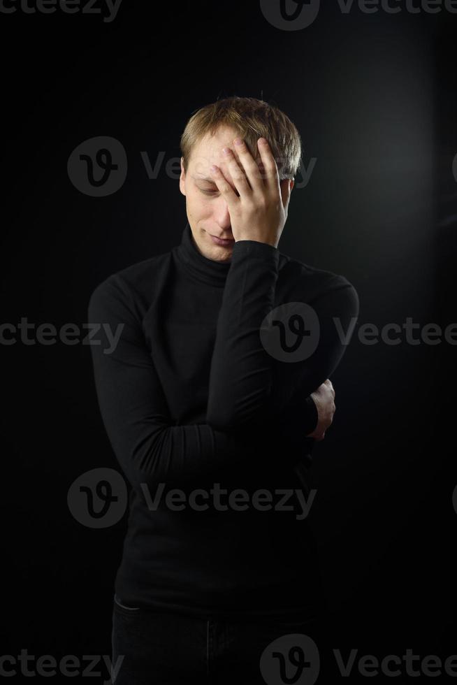 Portrait of determined goodlooking man wearing black shirt, black background. photo