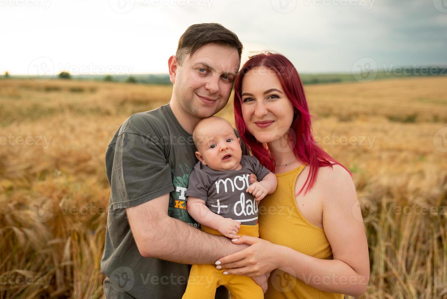 padre, madre y su pequeño hijo se divierten juntos en un campo de trigo. foto