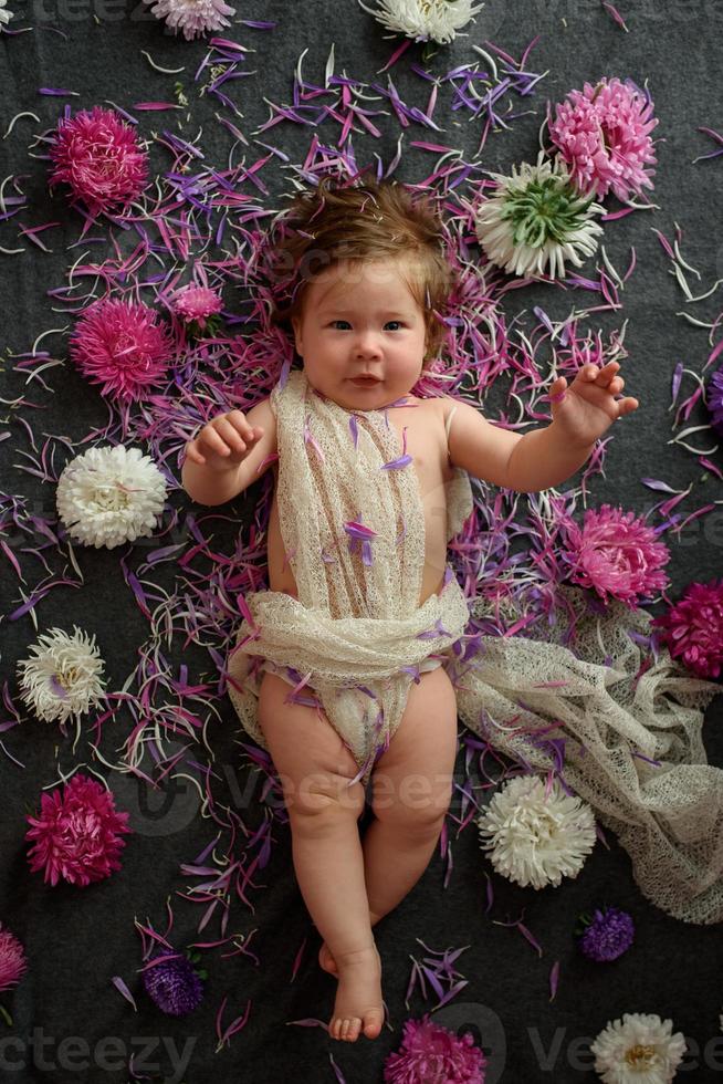 Portrait of a sweet little baby girl with a wreath of flowers on her head indoors photo