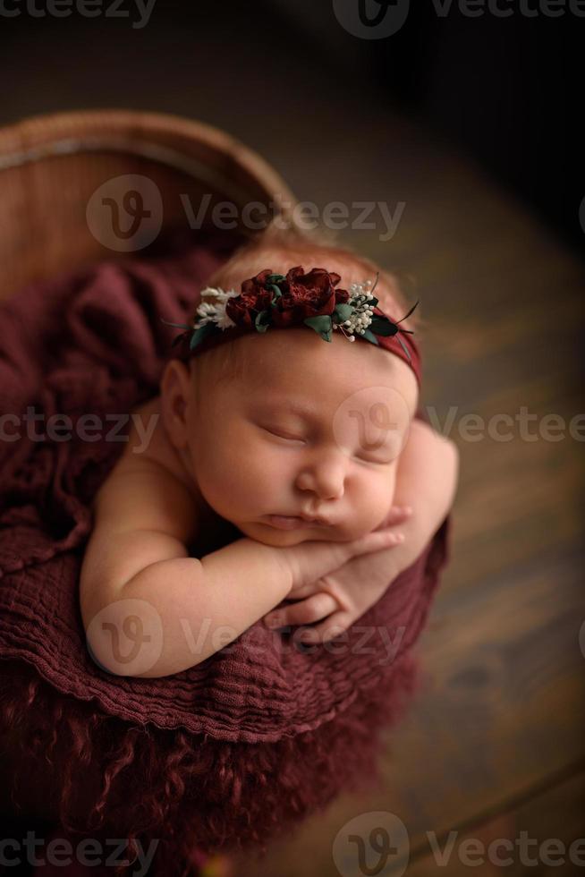 linda niña recién nacida durmiendo en una bañera sobre un fondo de madera. foto