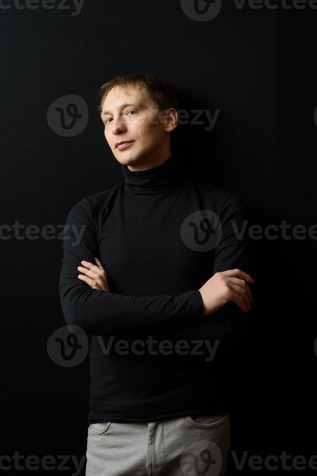 retrato de un hombre apuesto y decidido que usa camisa negra, fondo negro. foto