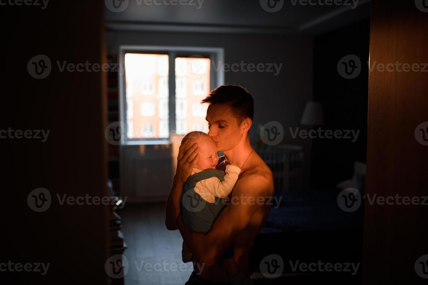 An adorable baby with father sonsoling close to the window photo