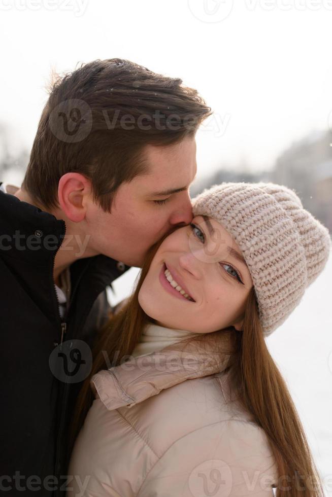 Young guy and girl in winterwear enjoying snowfall photo