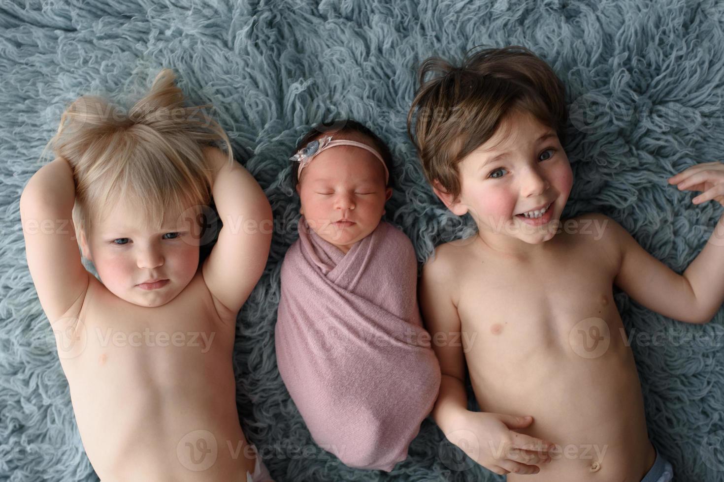 Two brothers will lie down next to his newborn sister. photo