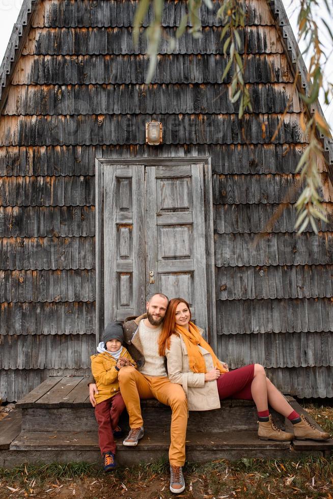 una familia feliz se sienta en los escalones frente a la entrada de la casa. foto