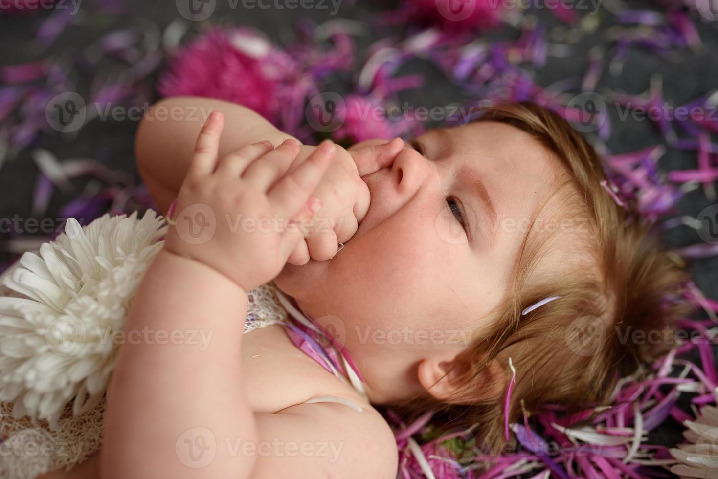 Portrait of a sweet little baby girl with a wreath of flowers on her head indoors photo