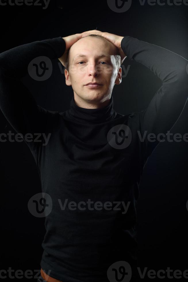 retrato de un hombre apuesto y decidido que usa camisa negra, fondo negro. foto