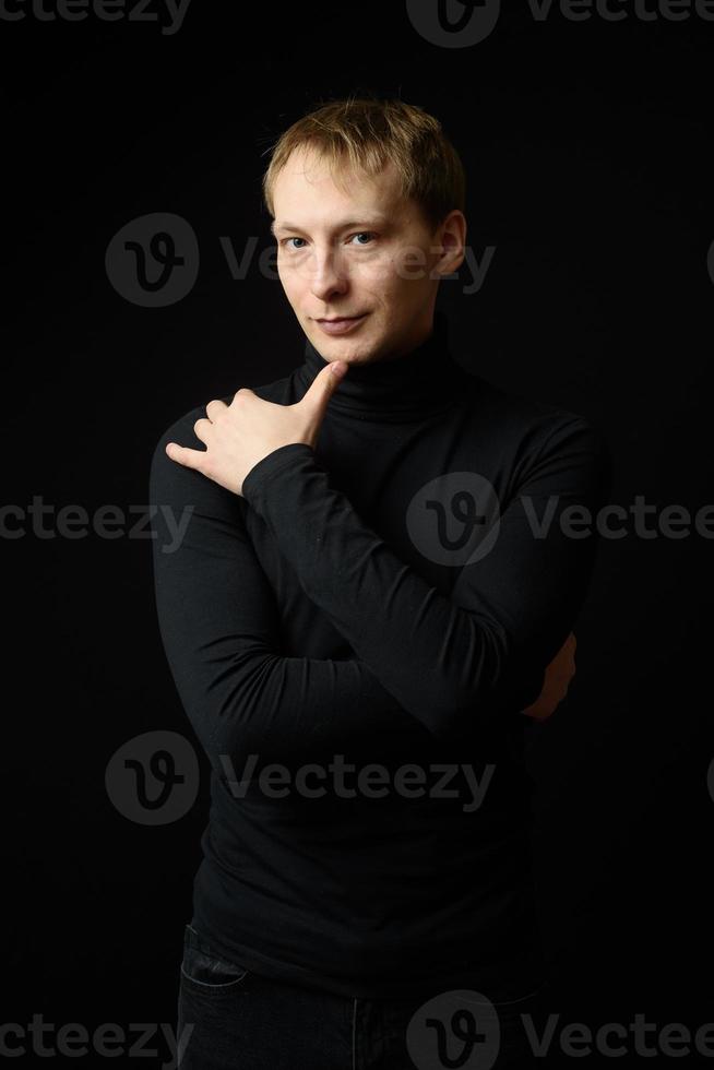 retrato de un hombre apuesto y decidido que usa camisa negra, fondo negro. foto