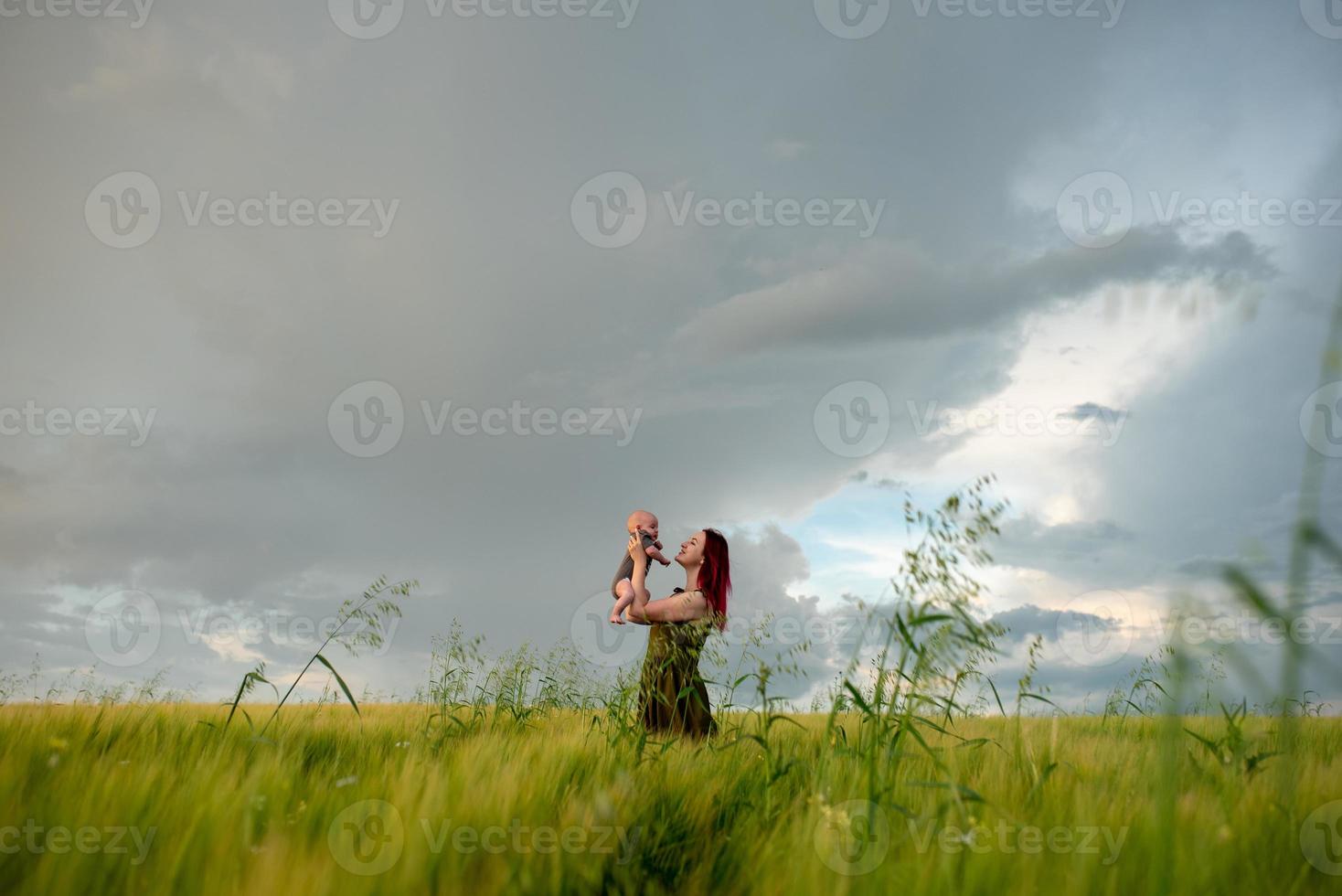 A mother tenderly holds her three month old son in her arms in a wheat field. photo