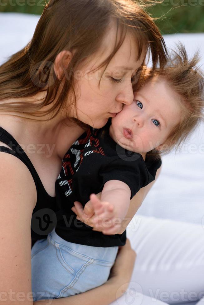 joven madre abrazando lindo bebé al aire libre foto