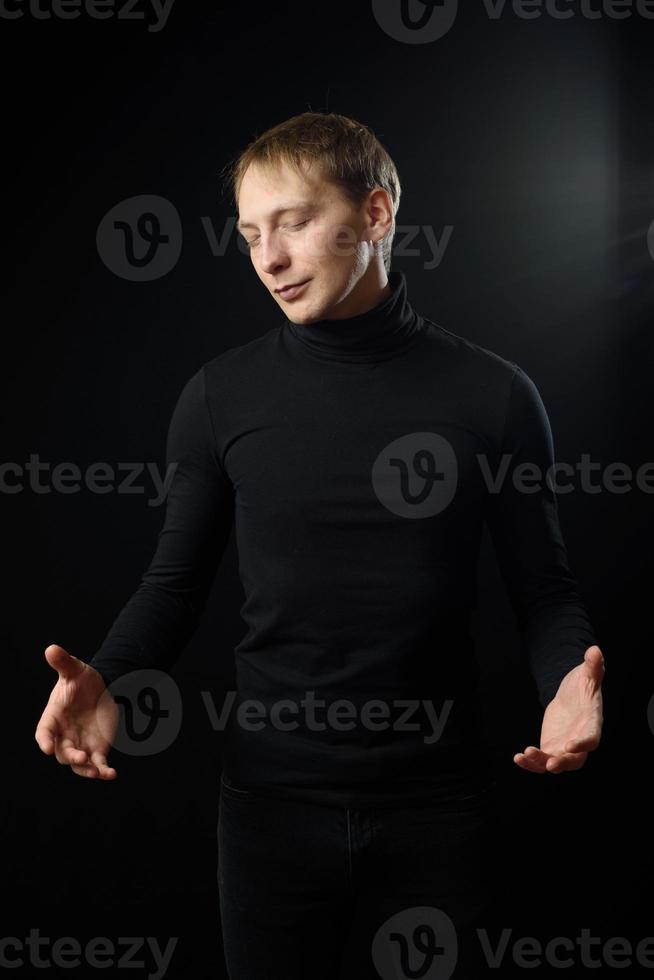 Portrait of determined goodlooking man wearing black shirt, black background. photo