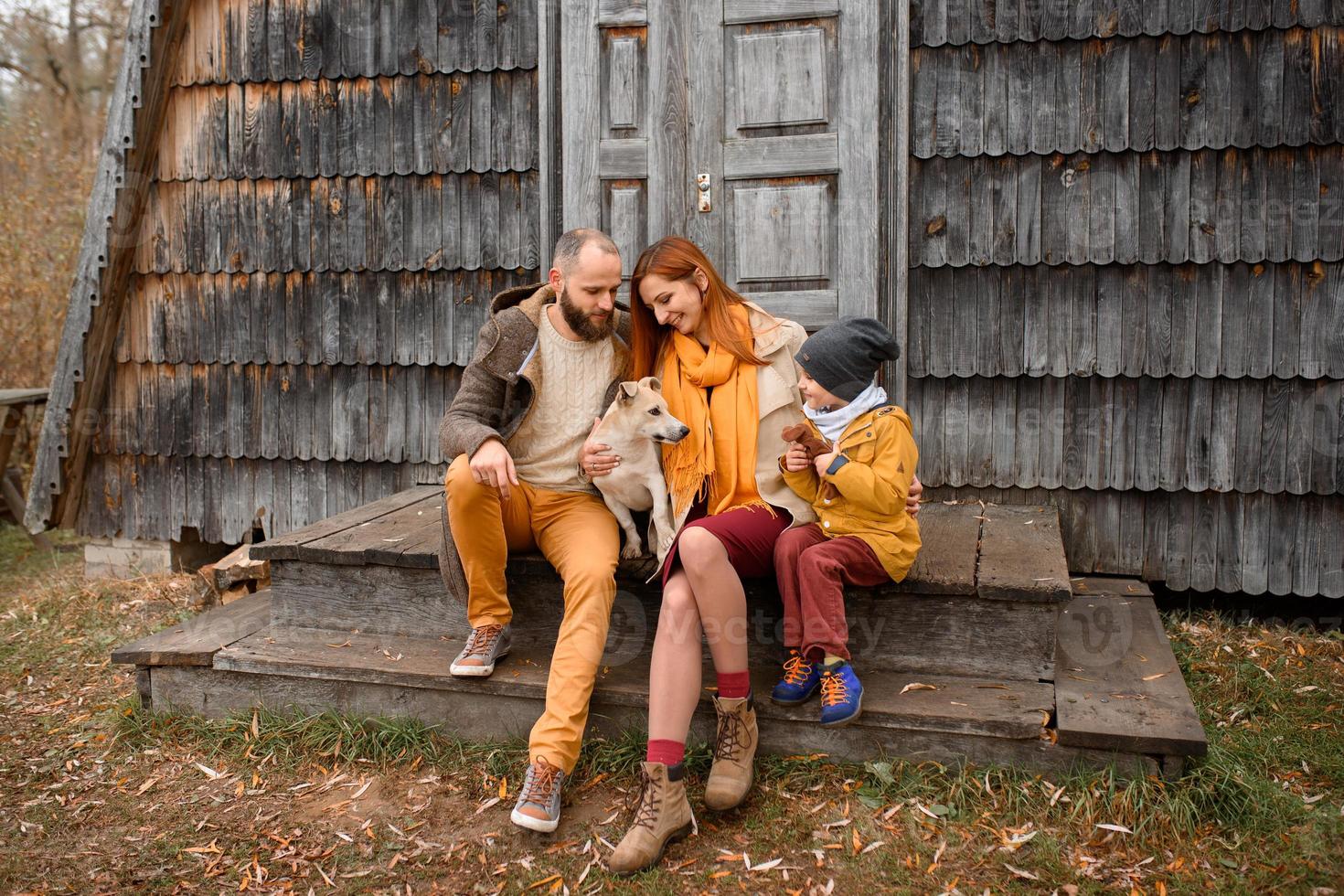a happy family sits on the steps in front of the entrance to the house. photo