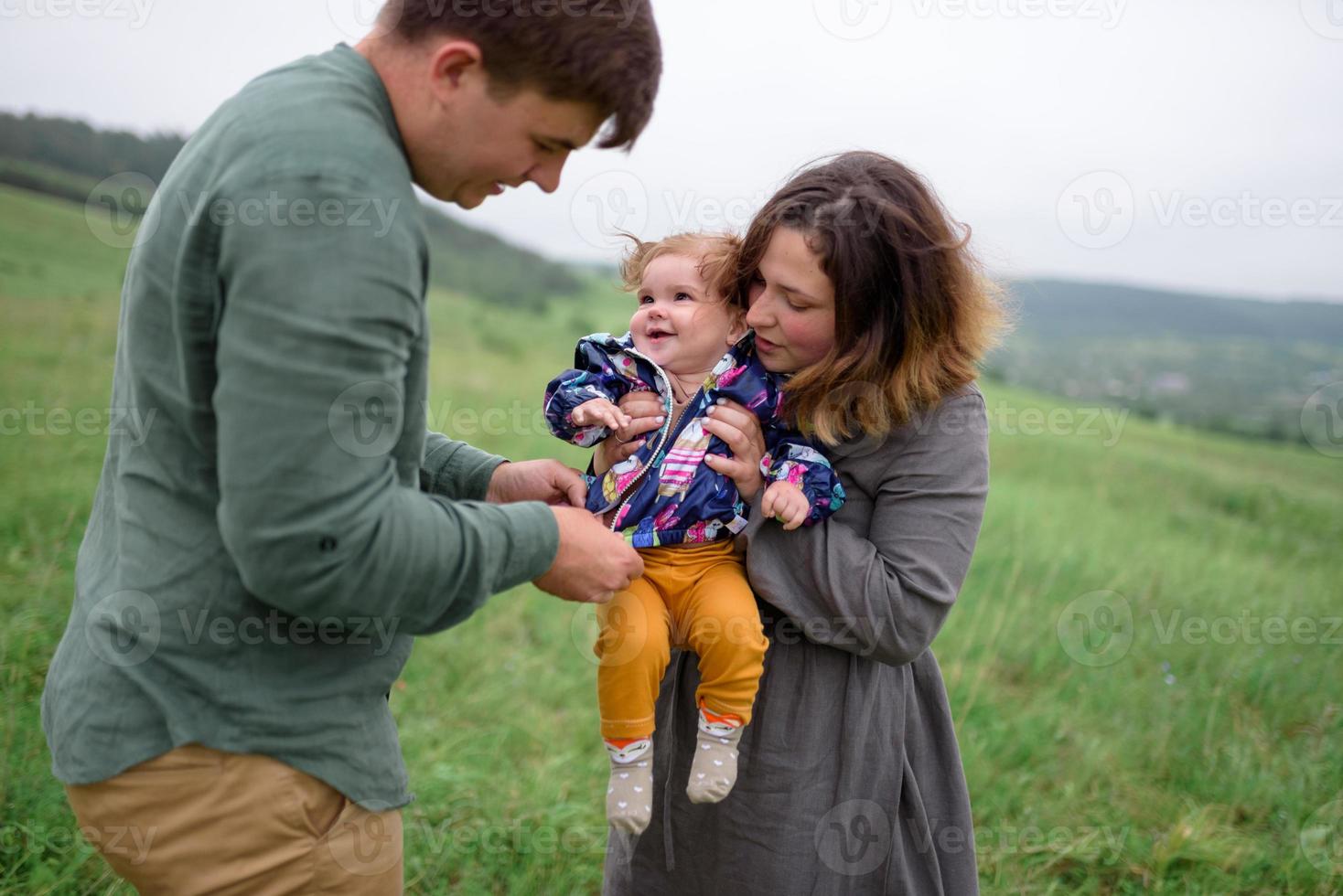 Mom, dad and daughter. Parents Hold baby by hands and go towards the camera. photo