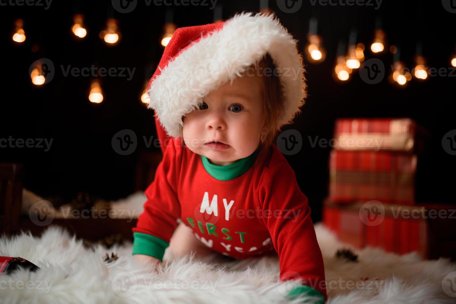 7 month old girl in a red Christmas costume on a background of retro garlands sits on a fur photo