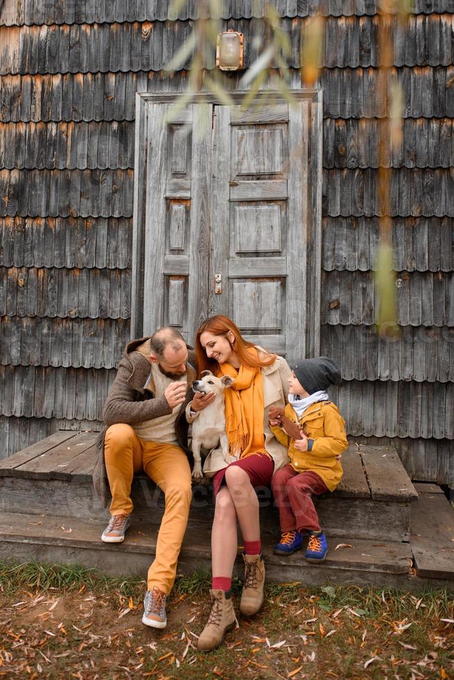 a happy family sits on the steps in front of the entrance to the house. photo