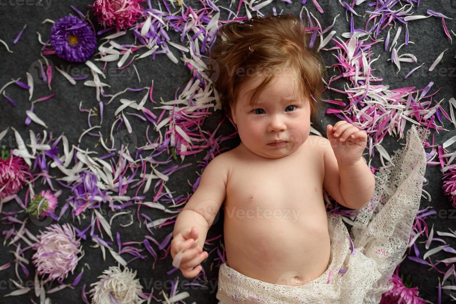 Portrait of a sweet little baby girl with a wreath of flowers on her head indoors photo