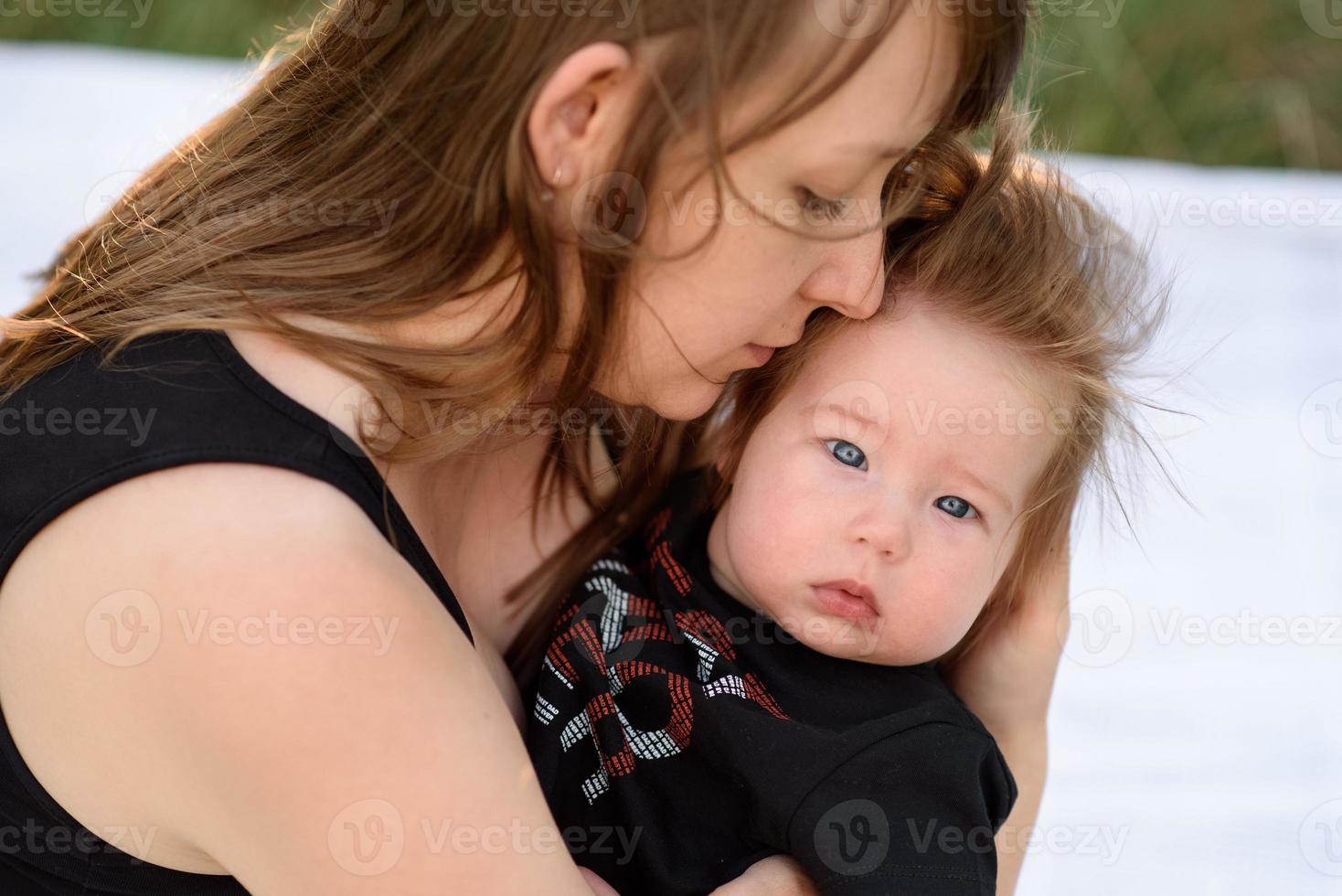 joven madre abrazando lindo bebé al aire libre foto