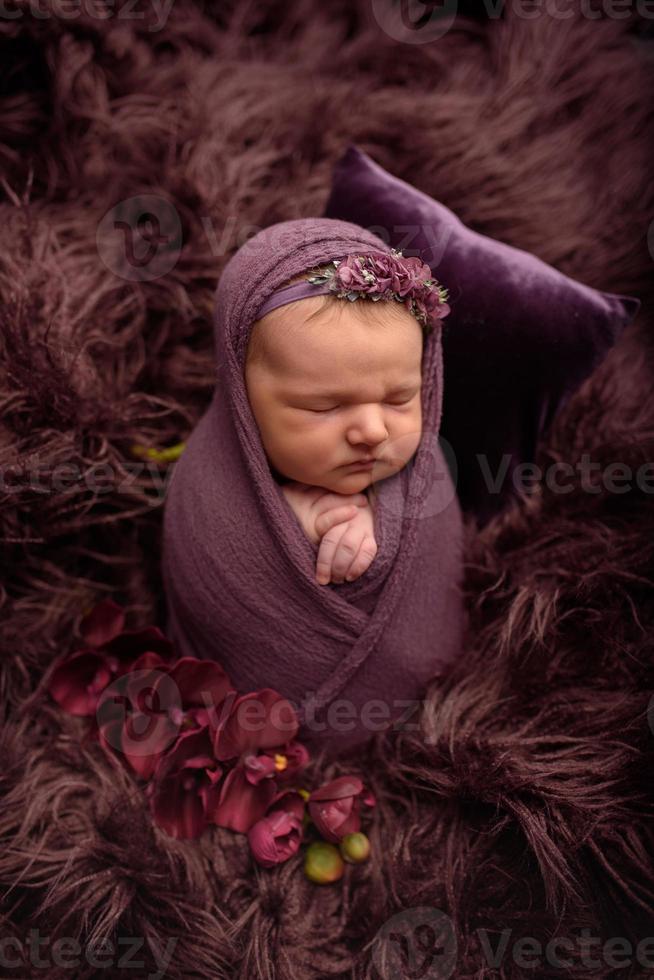 linda niña recién nacida durmiendo en un rebaño morado en una envoltura morada. foto