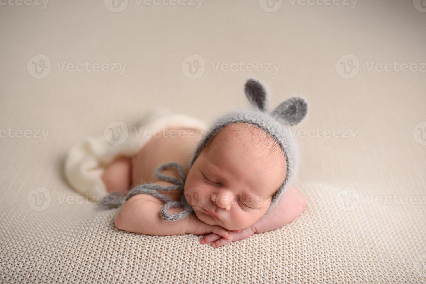 Newborn baby boy in a knitted hat sleeps on a light knitted blanket. photo