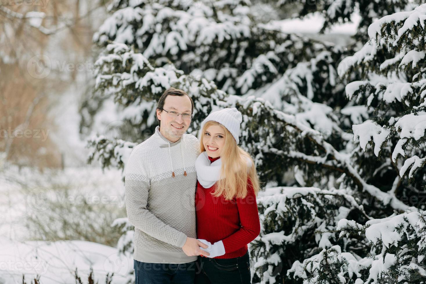 retrato de una pareja adulta feliz divirtiéndose en el bosque invernal y sonriendo, copiando espacio foto