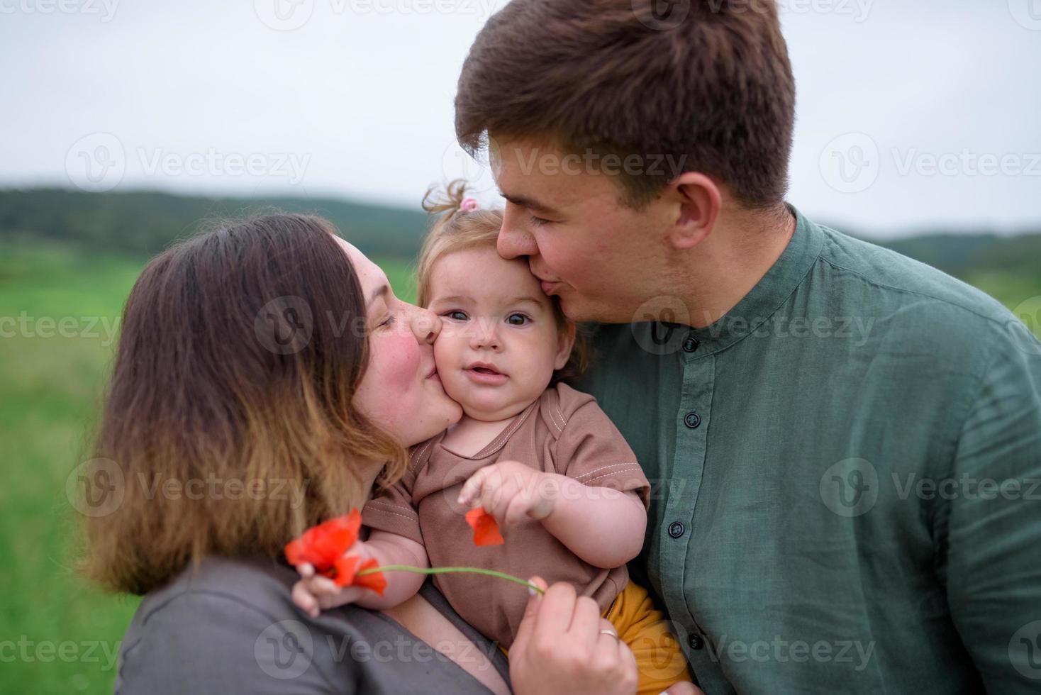 Mom, dad and daughter. Parents Hold baby by hands and go towards the camera. photo