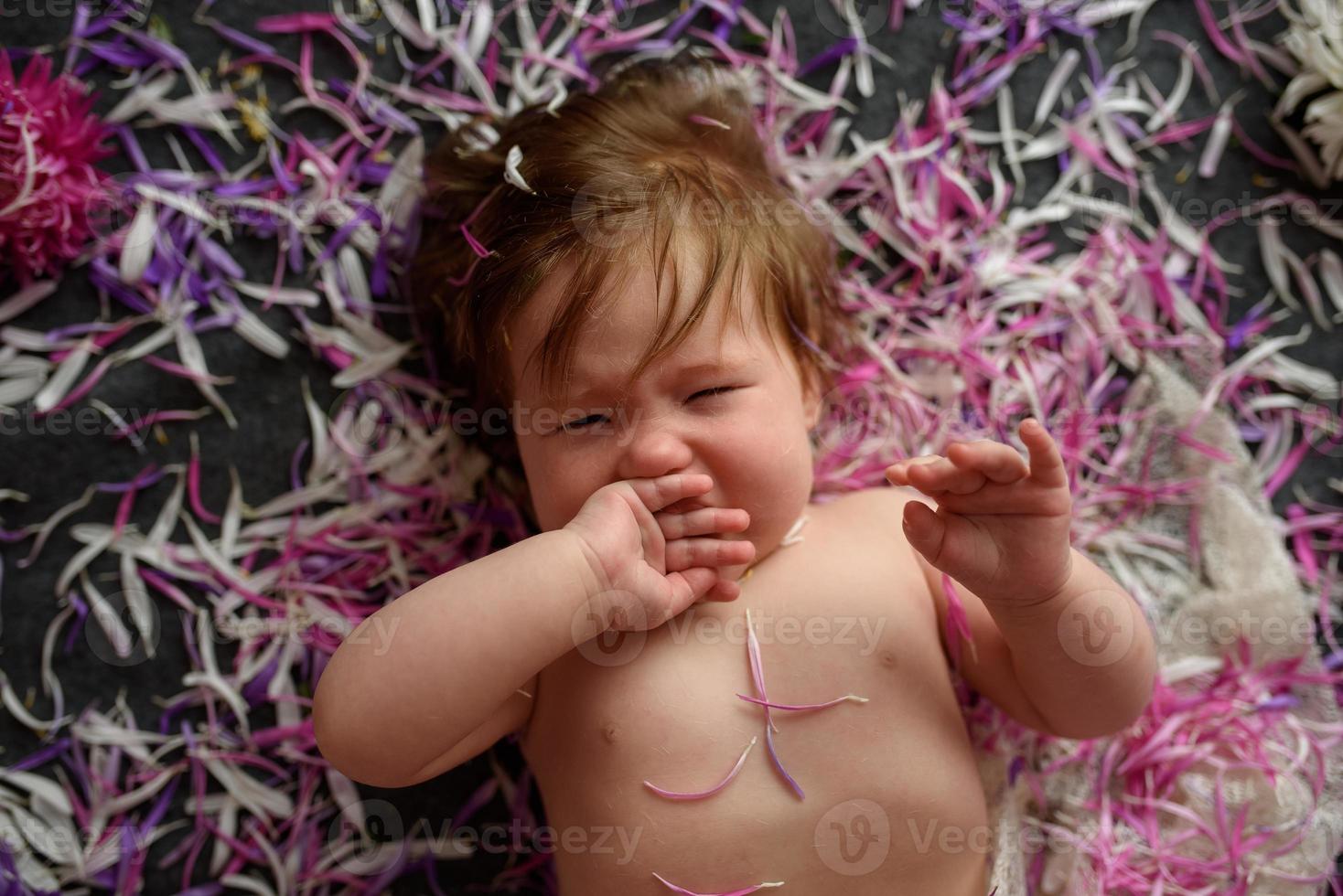 Portrait of a sweet little baby girl with a wreath of flowers on her head indoors photo