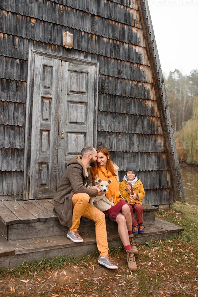 a happy family sits on the steps in front of the entrance to the house. photo