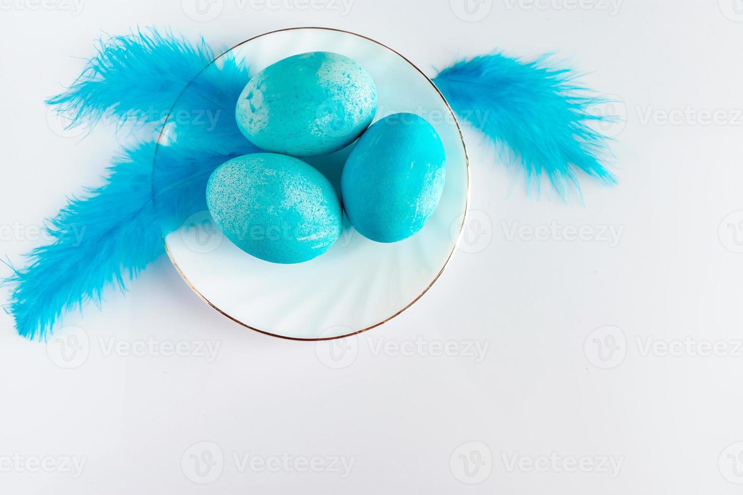 composición de huevos de pascua azules y plumas sobre un fondo claro. foto