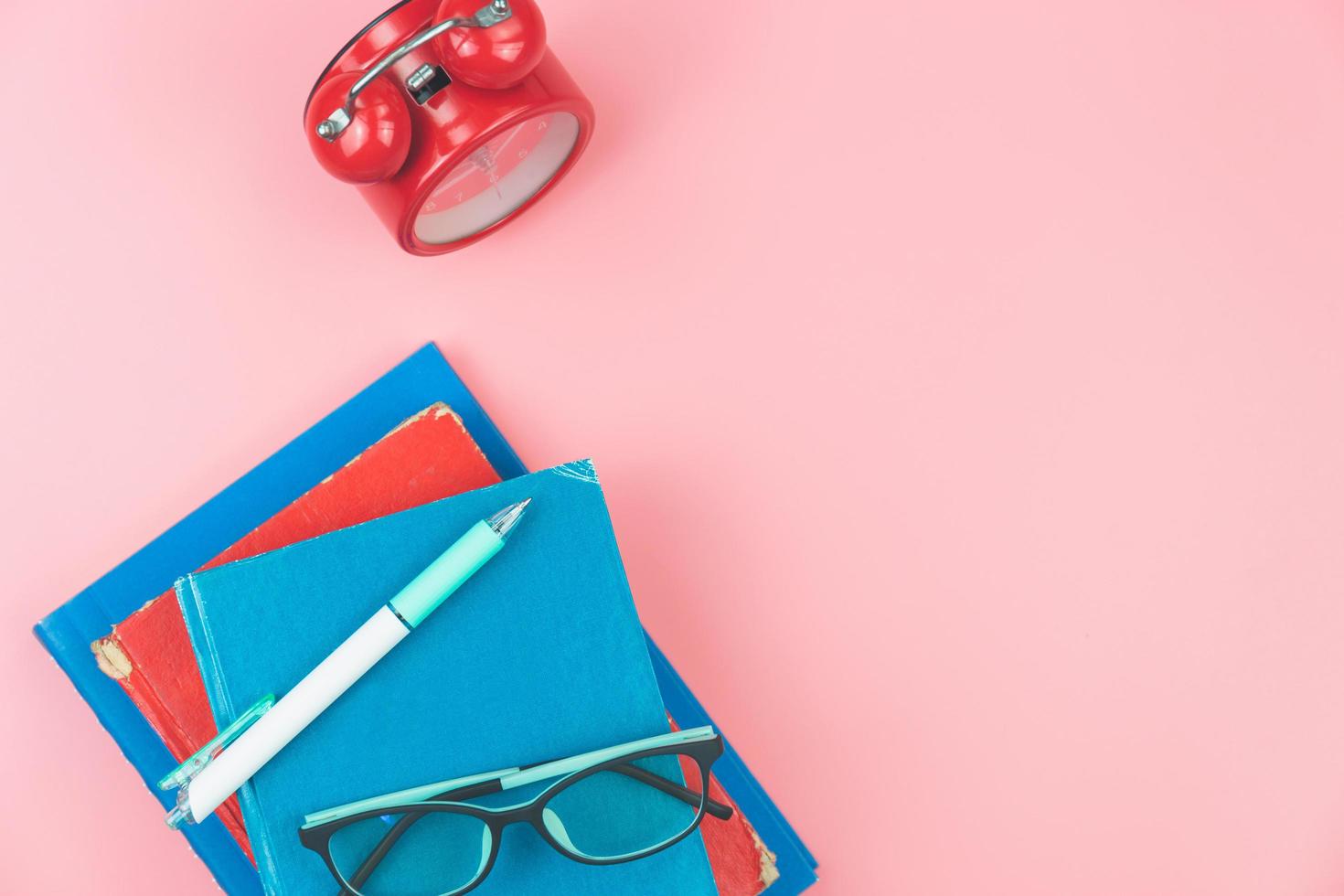 Top view with copy space of books, glasses, pen and clocks overhead on pink pastel background, Flat lay and education concept photo