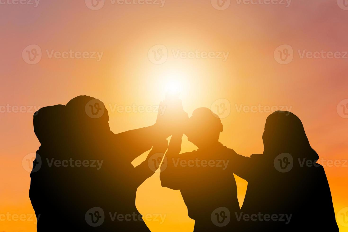 silueta de grupo de negocios celebrando después de la reunión, equipo de gente de negocios con recorte uniendo sus manos con alegría y éxito foto