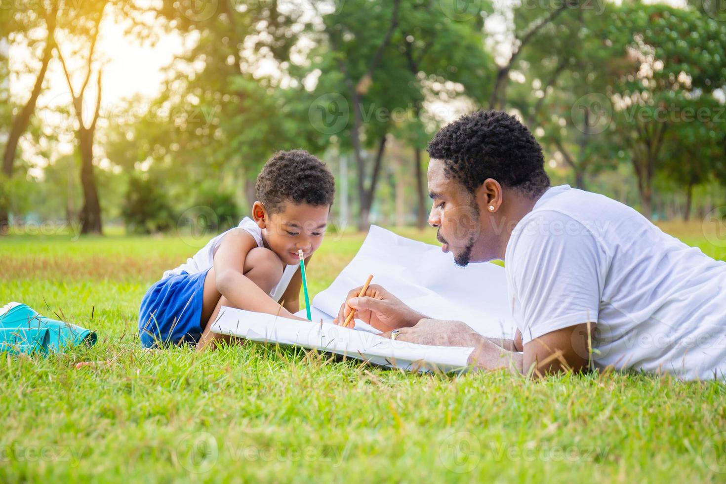 alegre padre afroamericano e hijo jugando en el parque, padres e hijos dibujando y pintando en el parque, conceptos familiares de felicidad foto