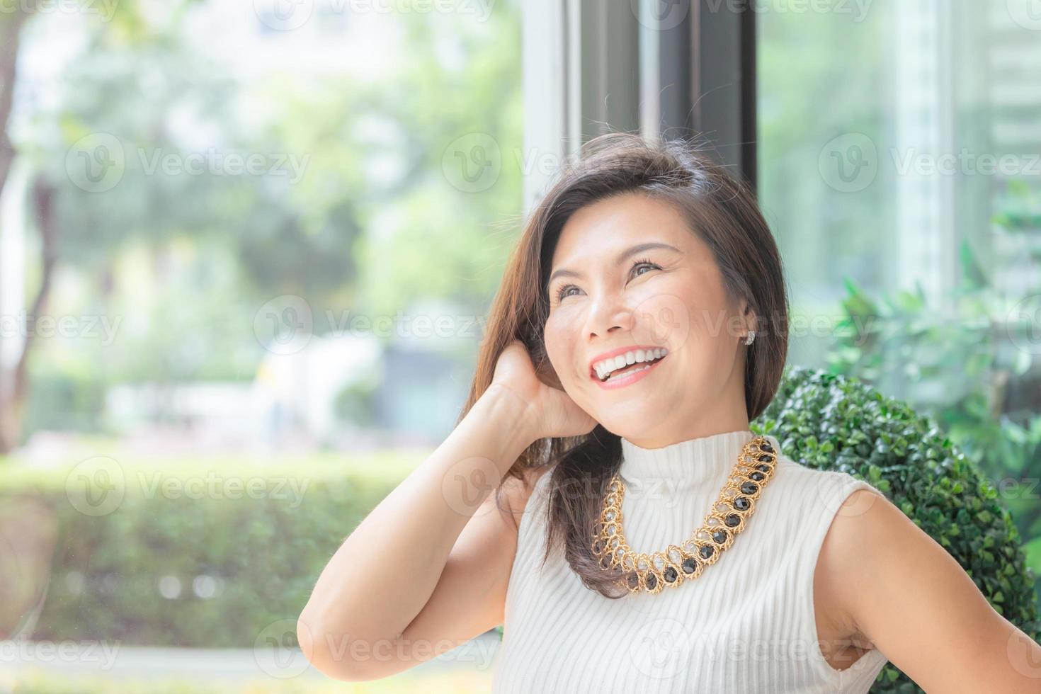 feliz, exitosa, inteligente, joven mujer de negocios asiática sentada, relajada y sonriente en el cargo. foto