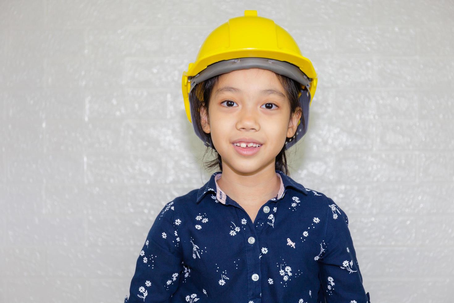 Dream career concept, Portrait of Happy engineer kid in hard hat looking at camera on blurred background photo