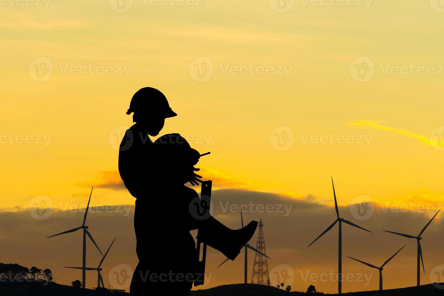 Silhouette of father and son with clipping path in hard hat, Happy dad carrying son on shoulders checking project at wind farm site on sunset in evening time photo