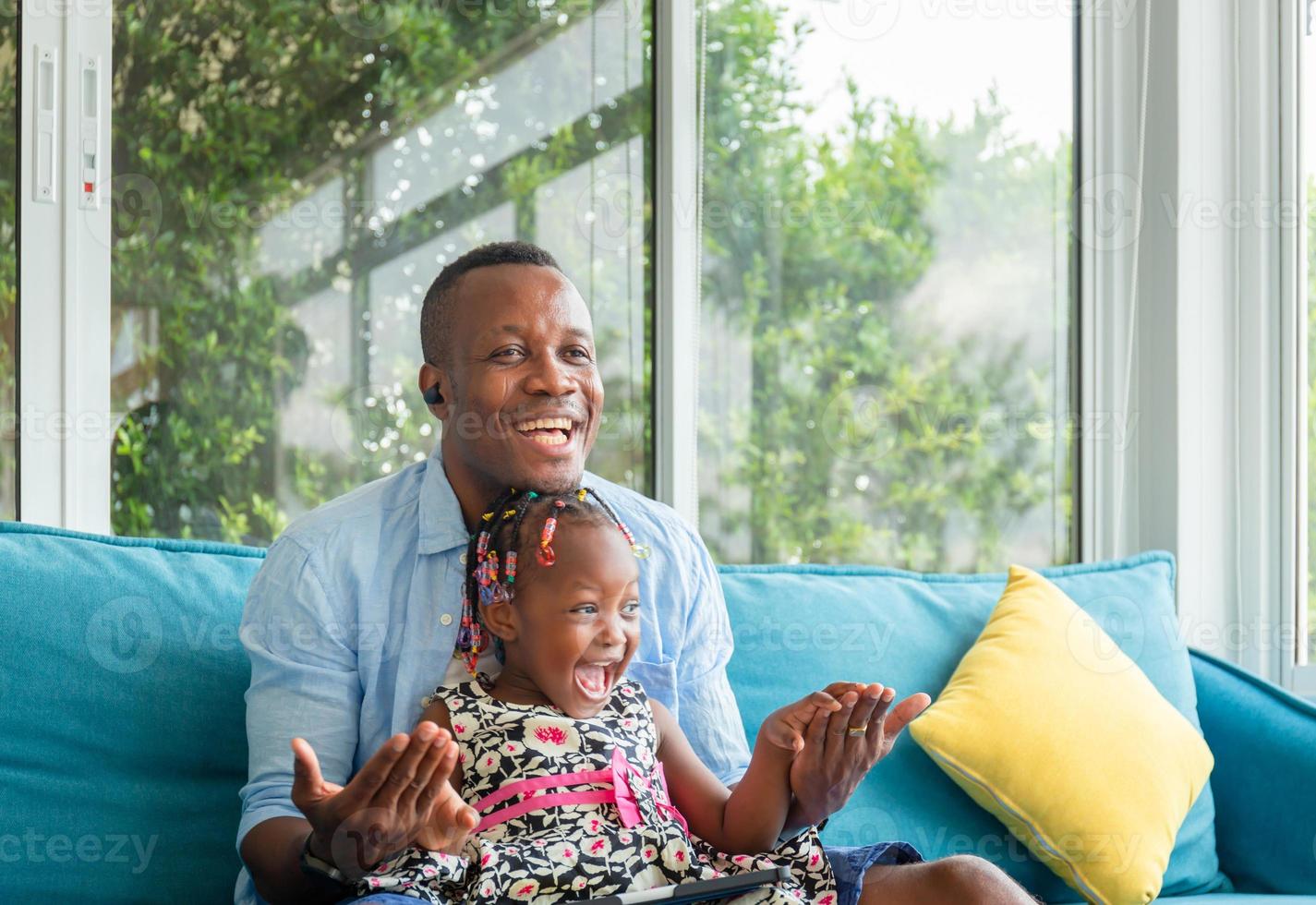 alegre padre afroamericano e hija jugando en la sala de estar, conceptos familiares de felicidad foto