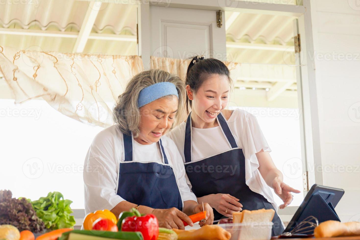 Senior asian mother and middle aged daughter cooking together at kitchen photo