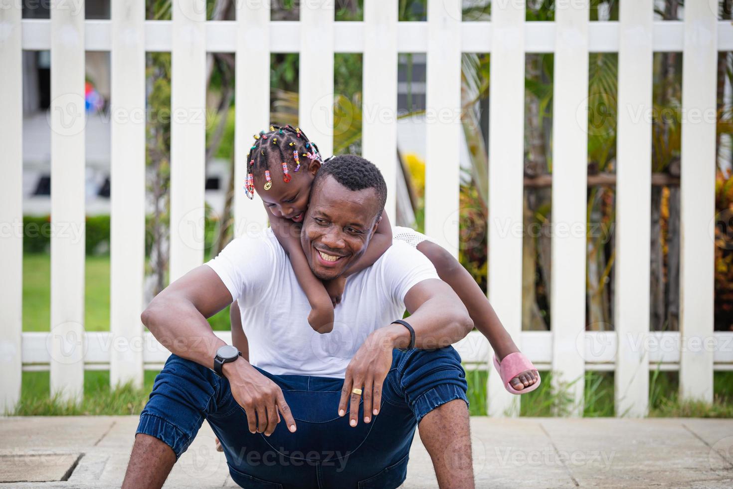 Cheerful African American kid girl hugging her father, Happy father and daughter laughing together outdoor photo