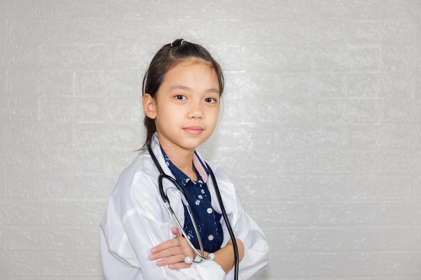 concepto de carrera de ensueño, retrato de un niño feliz con abrigo médico con estetoscopio en un fondo borroso foto