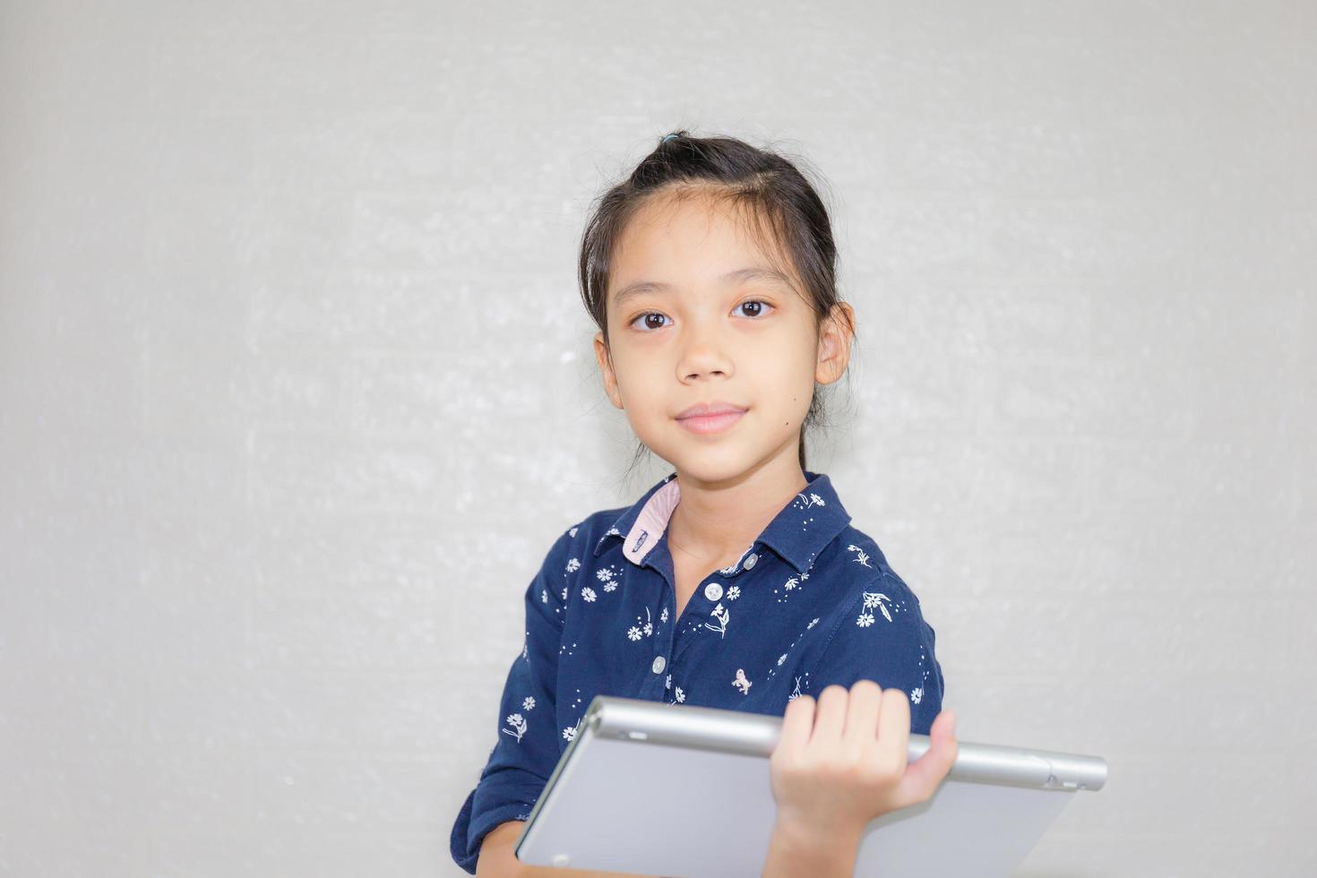 Little kid girl typing at wireless computer keyboard, Portrait of Happy child looking at camera with blurred background photo