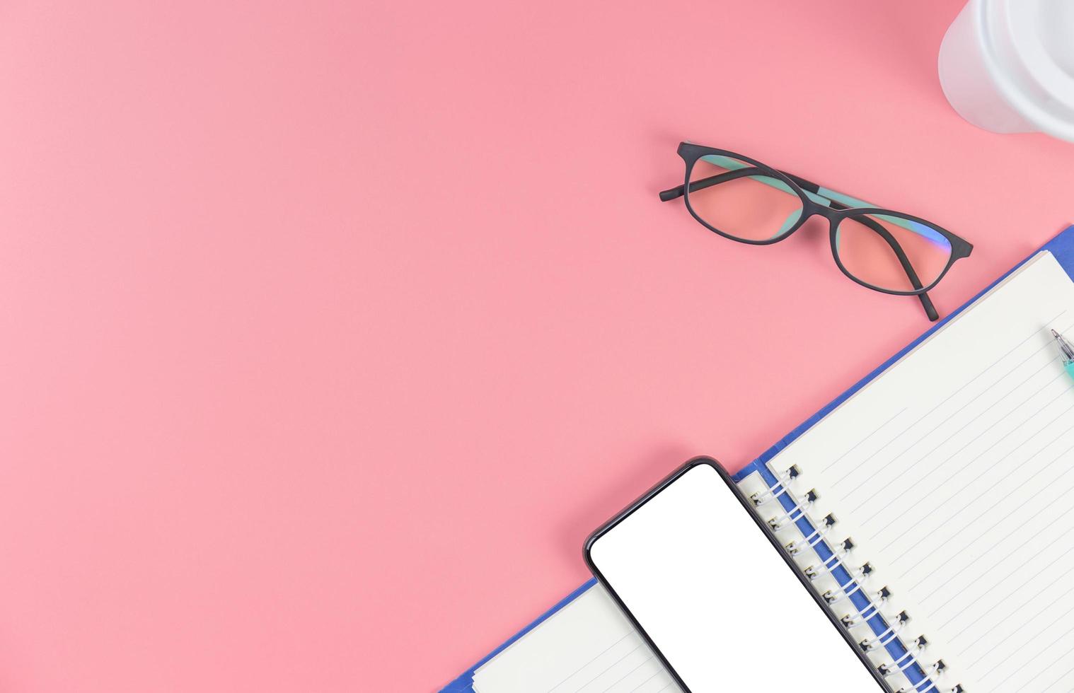 Top view with copy space of smartphone book glasses and pen overhead on pink pastel background, Flat lay and Mock up concept photo