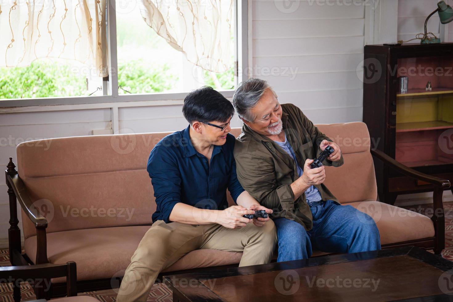 Padre asiático senior e hijo de mediana edad jugando videojuegos juntos en la sala de estar, conceptos familiares asiáticos de felicidad foto