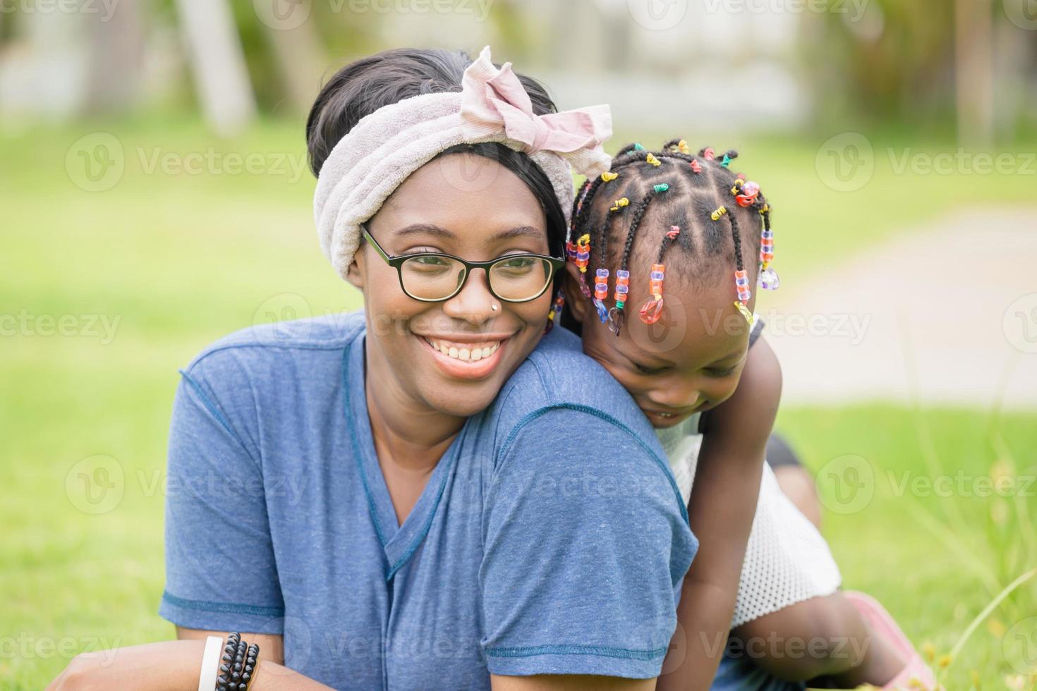 alegre niña afroamericana jugando en la espalda de su madre, feliz madre e hija riéndose juntas al aire libre foto