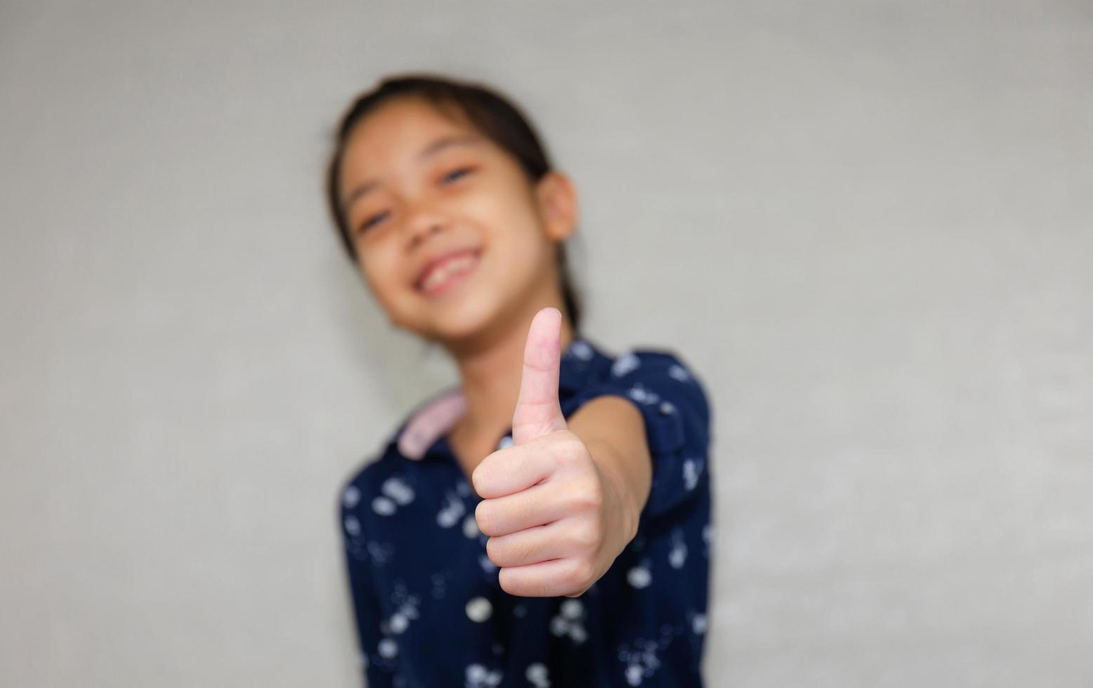 Cheerful little girl showing thumps up with blurred background photo