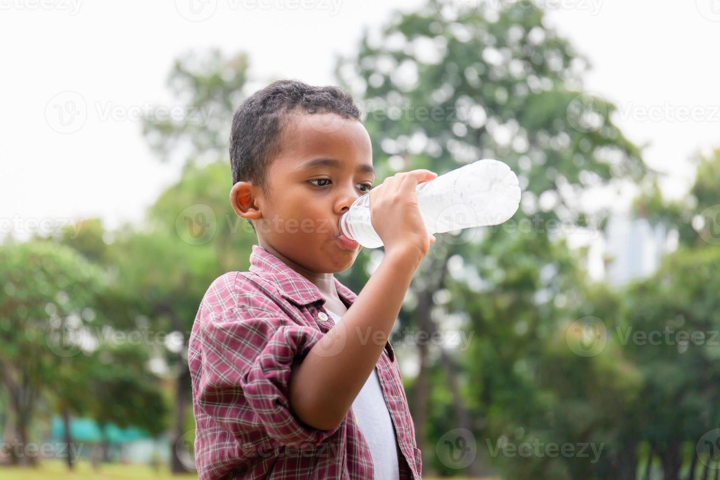 African American boy drinking water after playing at park photo