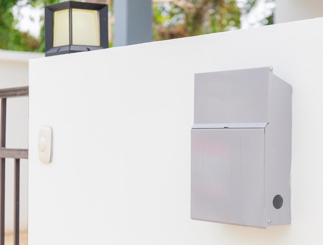 buzón de metal moderno en una pared de hormigón blanco con una casa moderna en el fondo foto